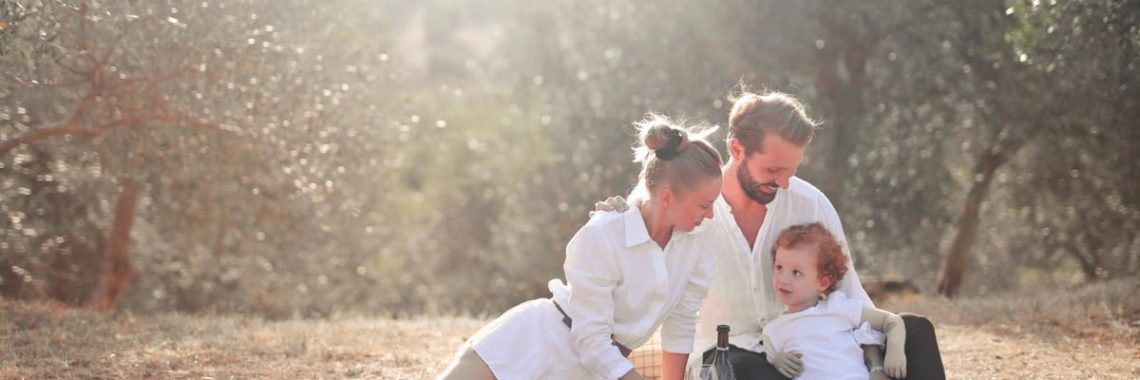Happy family enjoying a picnic in an olive grove under the sun. Perfect for lifestyle and outdoor themes.