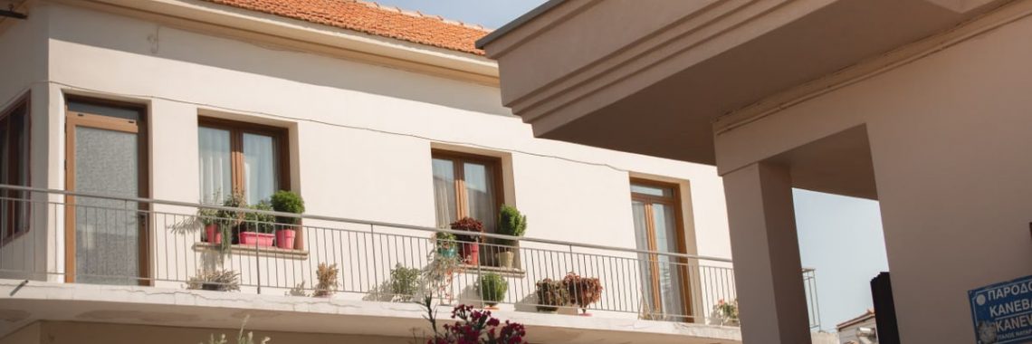 Traditional Greek house facade with potted plants and balcony details.